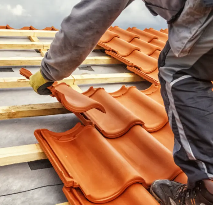 Couvreur professionnel réparant une toiture en tuiles sur une maison alsacienne à Colmar